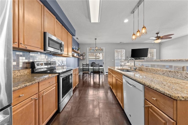 kitchen with pendant lighting, sink, backsplash, and appliances with stainless steel finishes