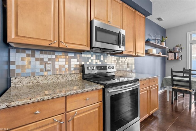 kitchen featuring light stone counters, decorative backsplash, stainless steel appliances, and a textured ceiling