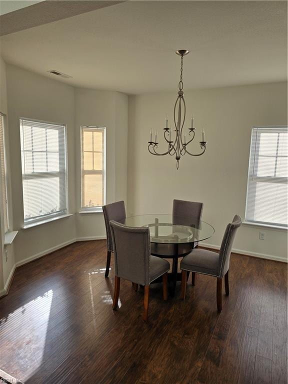 dining space with dark wood-type flooring and a chandelier