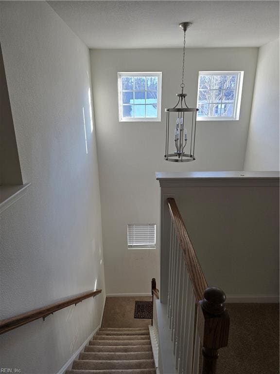 stairs featuring a notable chandelier, carpet, and a wealth of natural light