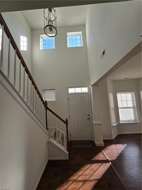 foyer with a healthy amount of sunlight, dark hardwood / wood-style floors, and a notable chandelier