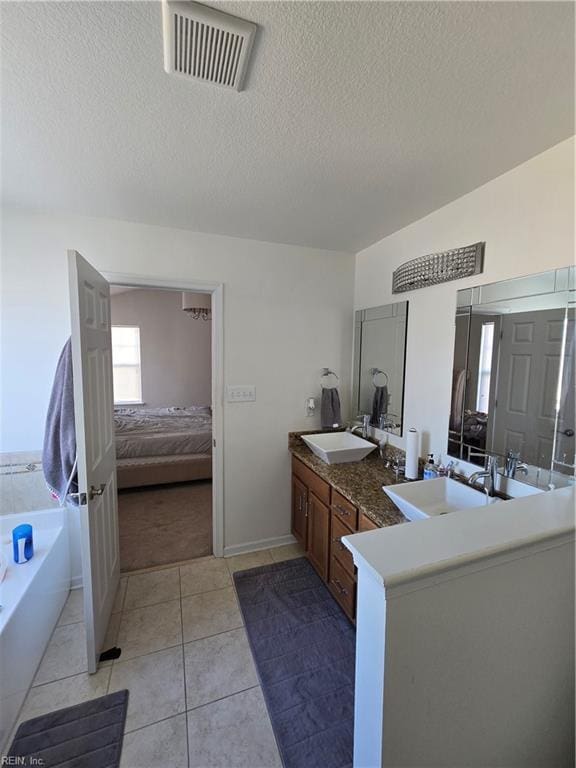 bathroom featuring vanity, tile patterned flooring, a textured ceiling, and a bathing tub