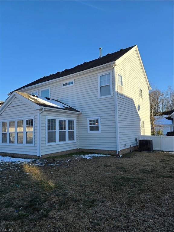 back of property featuring a yard and central AC