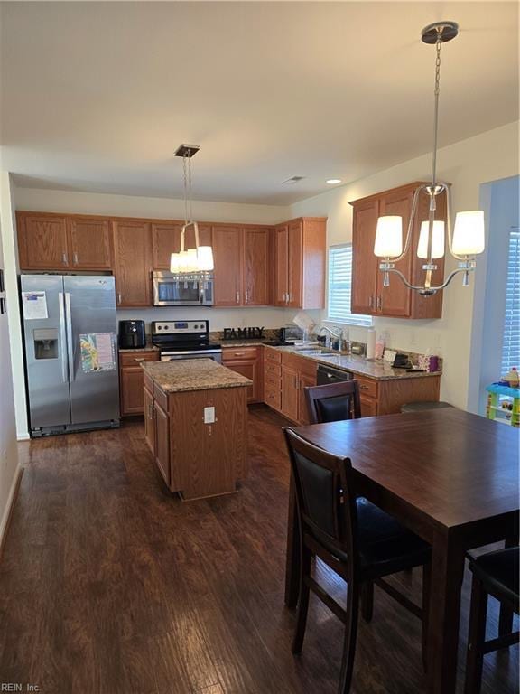 kitchen featuring a kitchen island, pendant lighting, sink, dark hardwood / wood-style flooring, and stainless steel appliances