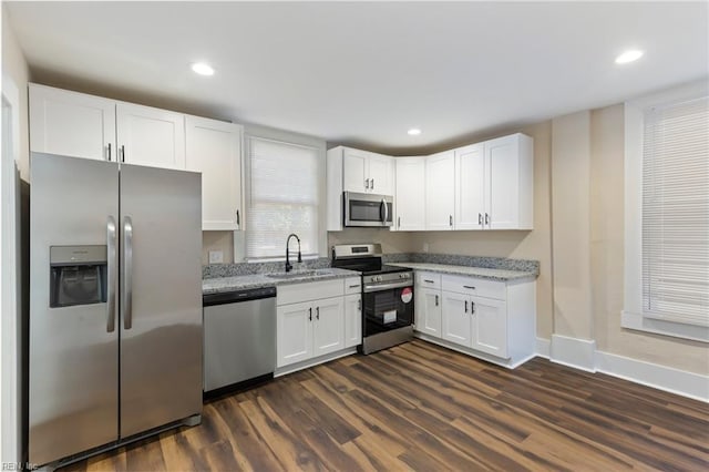 kitchen featuring white cabinetry, stainless steel appliances, light stone countertops, and sink