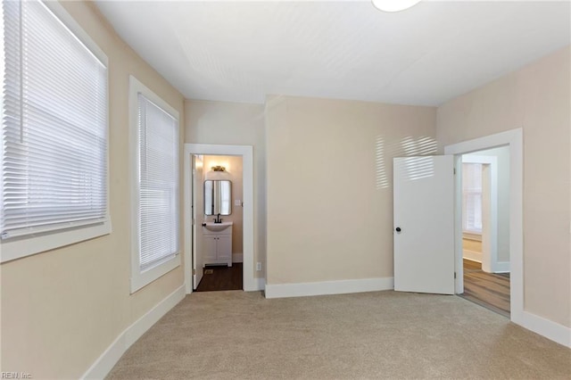 unfurnished bedroom featuring connected bathroom, sink, and light carpet