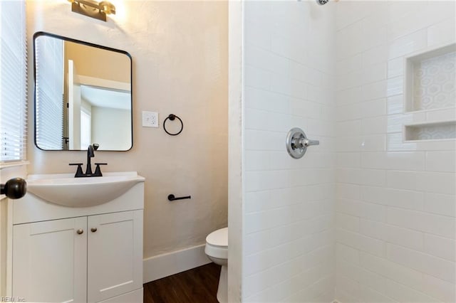 bathroom featuring vanity, toilet, hardwood / wood-style floors, and a tile shower