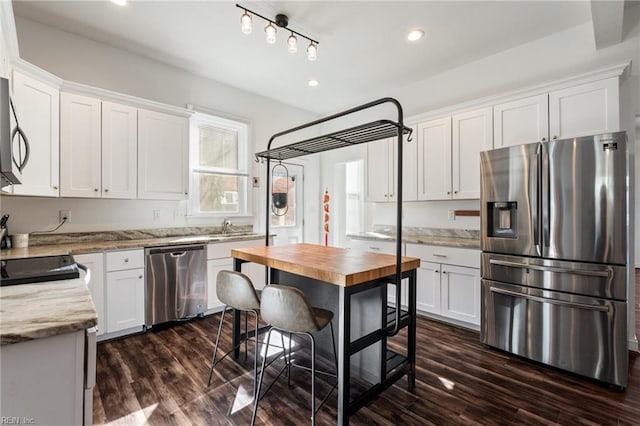 kitchen with white cabinetry, stainless steel appliances, dark hardwood / wood-style flooring, and light stone counters