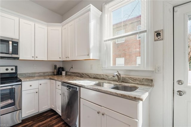 kitchen featuring appliances with stainless steel finishes, light stone countertops, sink, and white cabinets