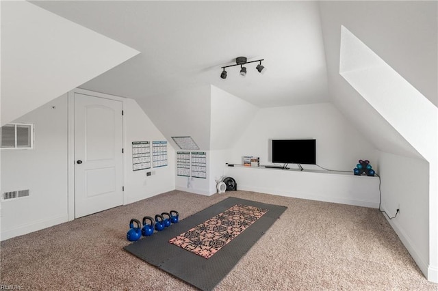 interior space featuring track lighting, lofted ceiling, and carpet