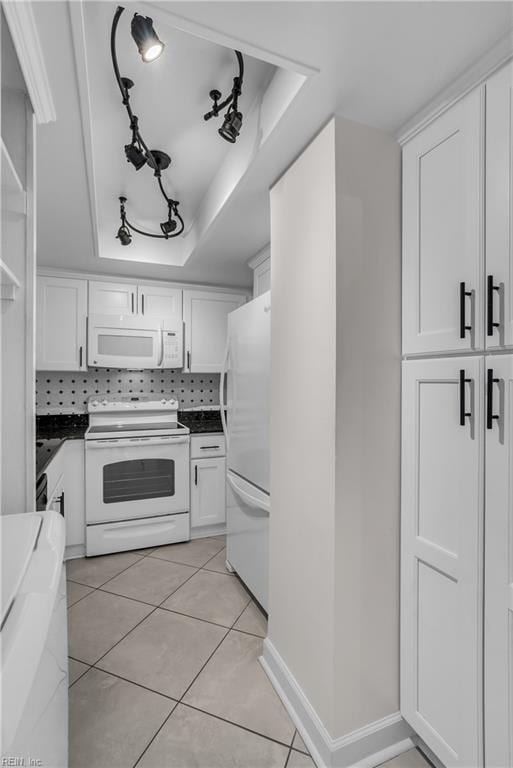 kitchen featuring white appliances, white cabinets, light tile patterned flooring, decorative backsplash, and a raised ceiling