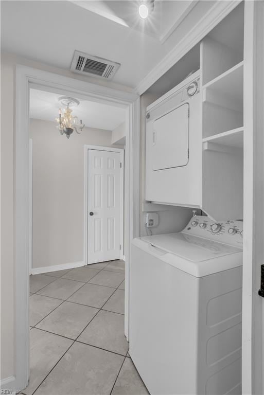 laundry room with light tile patterned flooring, stacked washer and clothes dryer, and a notable chandelier