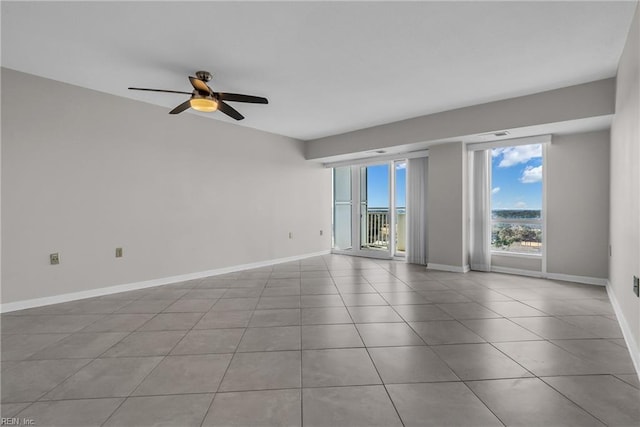 tiled empty room featuring plenty of natural light and ceiling fan