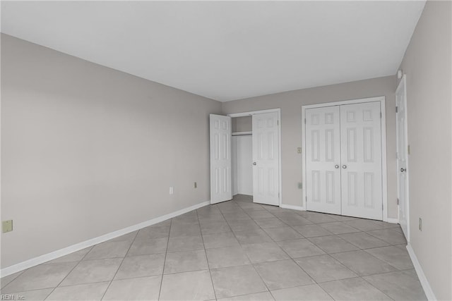 unfurnished bedroom featuring light tile patterned floors and two closets