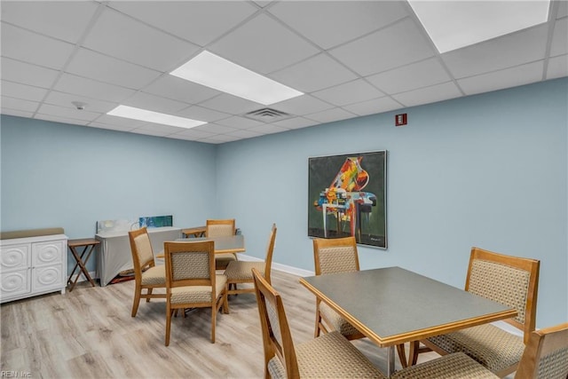 dining area with a drop ceiling and light hardwood / wood-style flooring