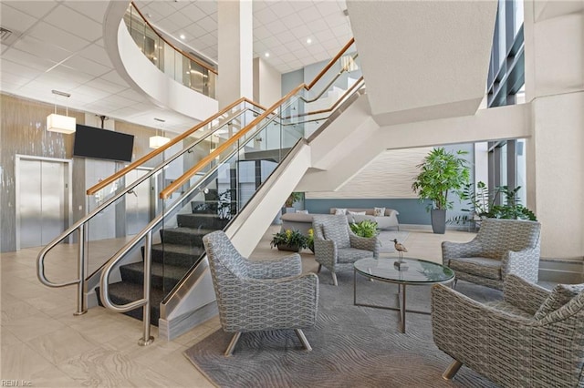 stairs with elevator, wooden walls, a paneled ceiling, and a high ceiling