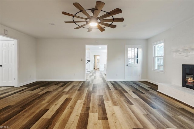 unfurnished living room featuring dark wood-type flooring and ceiling fan