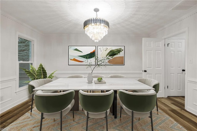 dining space featuring crown molding, hardwood / wood-style floors, and a notable chandelier