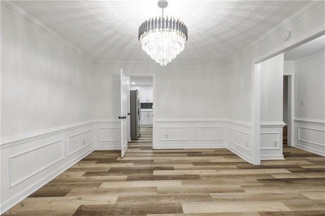 unfurnished dining area featuring crown molding, a chandelier, and light hardwood / wood-style floors