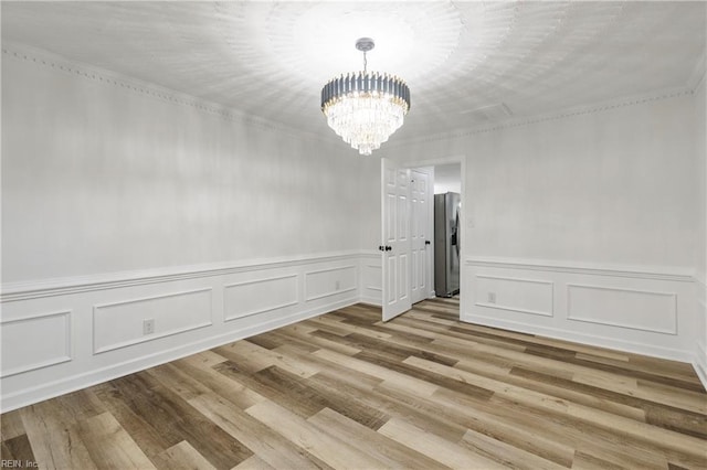 unfurnished room featuring crown molding, a chandelier, and light hardwood / wood-style flooring