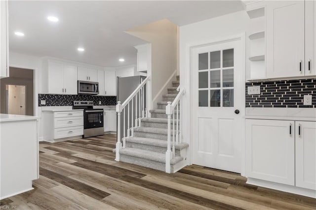 kitchen with white cabinetry, decorative backsplash, dark hardwood / wood-style flooring, and stainless steel appliances