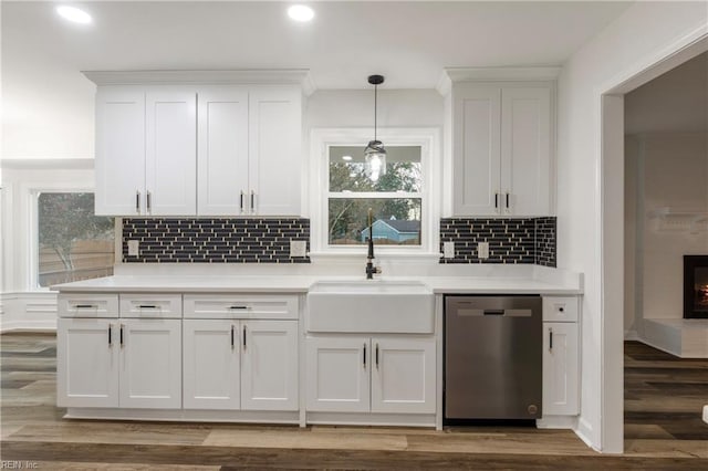 kitchen featuring white cabinetry, sink, stainless steel dishwasher, and decorative light fixtures