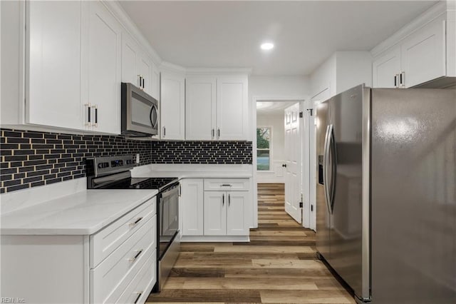 kitchen with white cabinetry, backsplash, stainless steel appliances, wood-type flooring, and light stone countertops