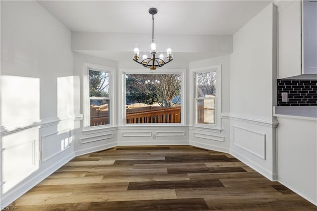 unfurnished dining area featuring hardwood / wood-style flooring, plenty of natural light, and an inviting chandelier