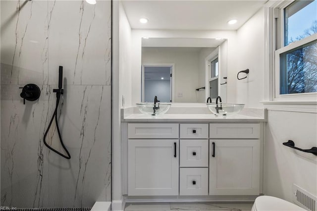 bathroom with tiled shower and vanity