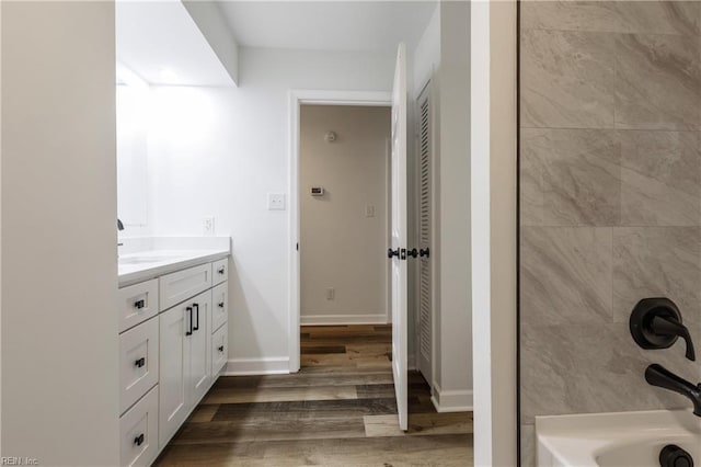 bathroom with hardwood / wood-style flooring, washtub / shower combination, and vanity