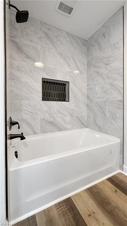 bathroom featuring hardwood / wood-style flooring and tiled shower / bath