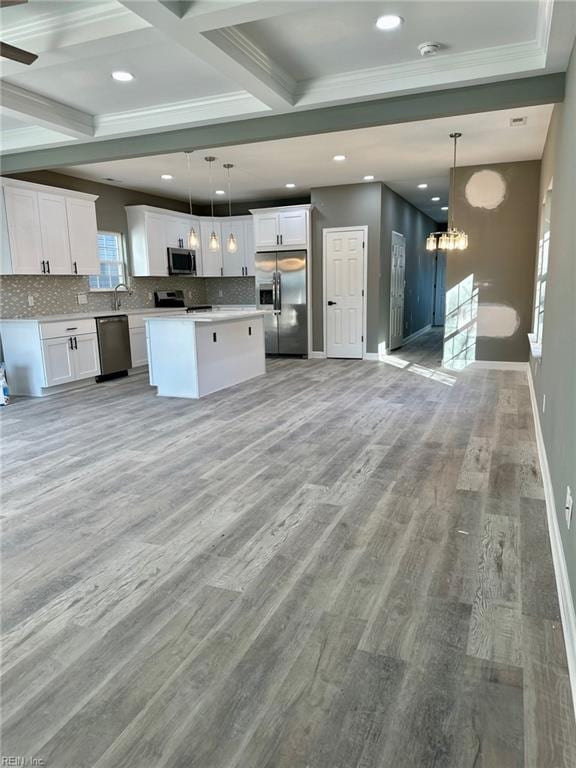 kitchen with appliances with stainless steel finishes, decorative light fixtures, a kitchen island, and white cabinets