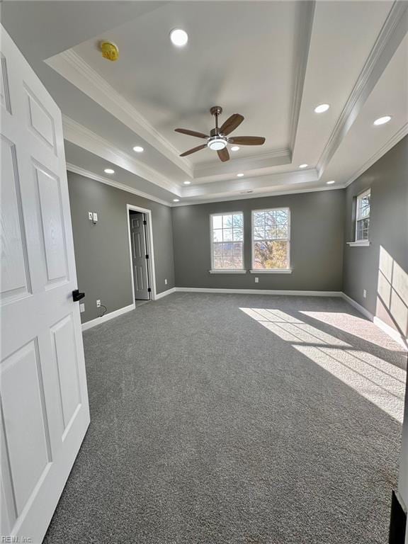 carpeted spare room with crown molding, ceiling fan, and a tray ceiling