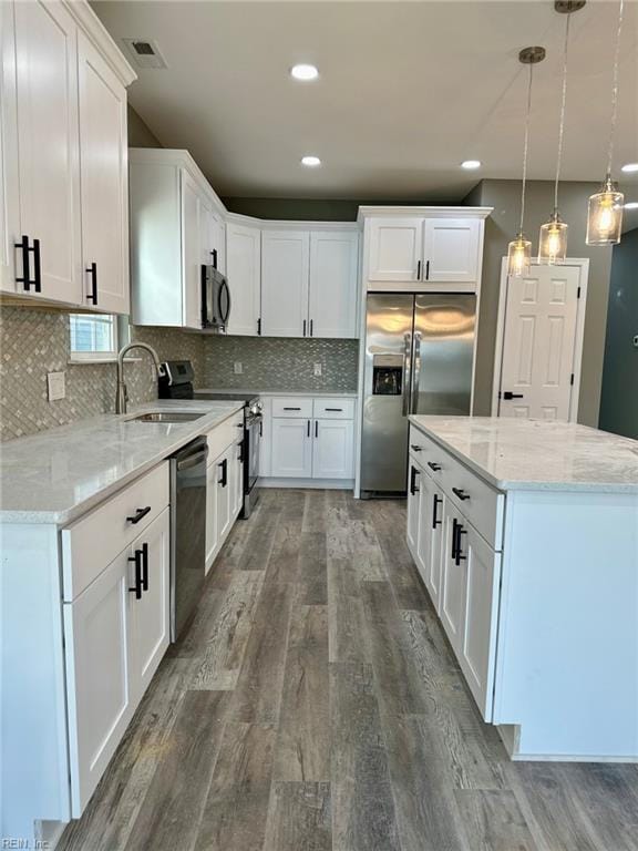 kitchen featuring pendant lighting, sink, white cabinets, light stone counters, and stainless steel appliances