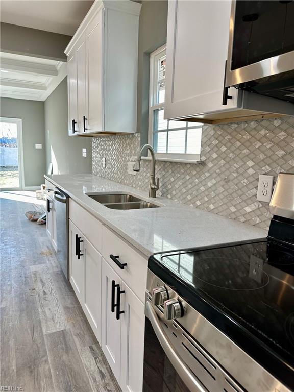 kitchen featuring stainless steel appliances, light stone countertops, sink, and white cabinets