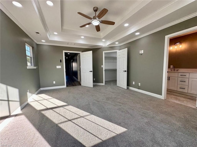 unfurnished bedroom with sink, a tray ceiling, ornamental molding, and light colored carpet