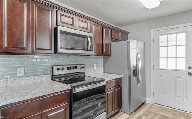 kitchen featuring dark brown cabinetry, appliances with stainless steel finishes, backsplash, and light hardwood / wood-style floors