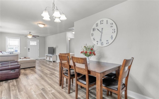 dining area with ceiling fan with notable chandelier and light hardwood / wood-style flooring