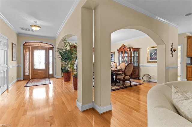 entrance foyer featuring ornamental molding and light hardwood / wood-style floors