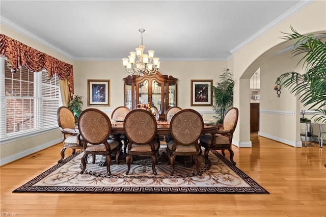 dining room with ornamental molding, wood-type flooring, and a chandelier