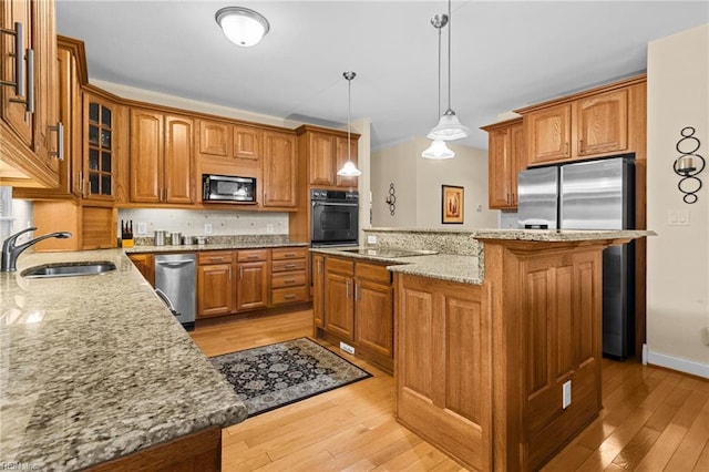 kitchen featuring a kitchen island, sink, hanging light fixtures, stainless steel appliances, and light wood-type flooring