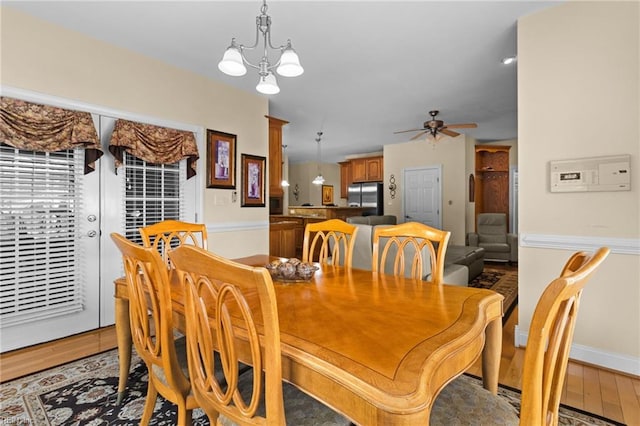 dining area featuring ceiling fan with notable chandelier and light hardwood / wood-style flooring