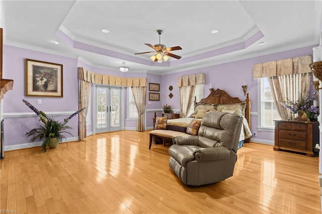 bedroom with a tray ceiling, access to outside, french doors, and light wood-type flooring