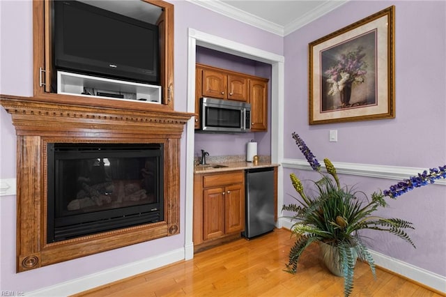 kitchen with sink, ornamental molding, light hardwood / wood-style floors, and appliances with stainless steel finishes