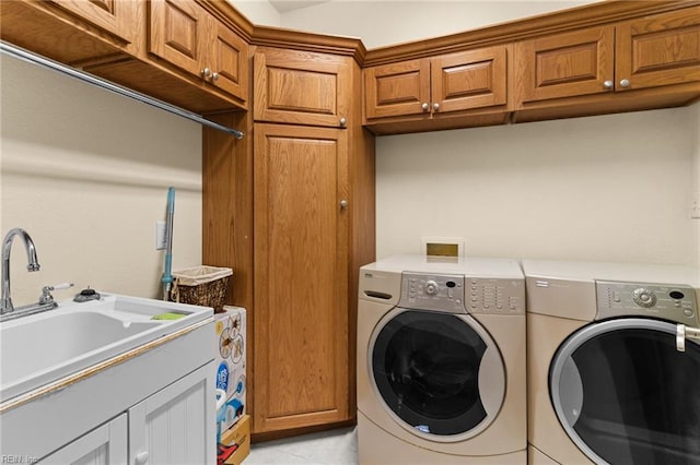 clothes washing area featuring sink, cabinets, washing machine and clothes dryer, and light tile patterned flooring