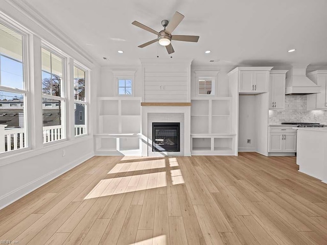 unfurnished living room with ceiling fan, ornamental molding, a fireplace, and light hardwood / wood-style flooring