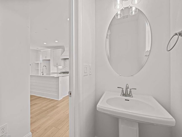 bathroom with hardwood / wood-style flooring, sink, and backsplash