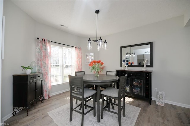 dining area with wood-type flooring and a chandelier