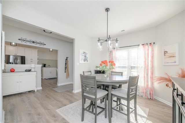 dining space with a notable chandelier and light hardwood / wood-style floors