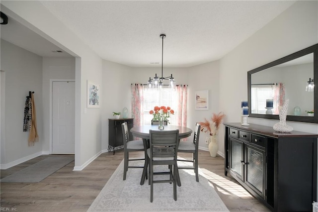 dining space with a notable chandelier and light hardwood / wood-style floors